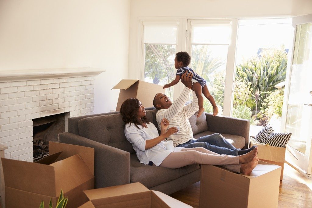 family sitting in the sofa in their new home surrounded by unpacked boxes