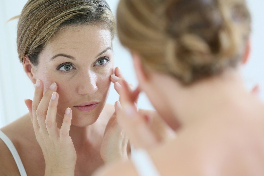 woman looking at her eyebags in the mirror