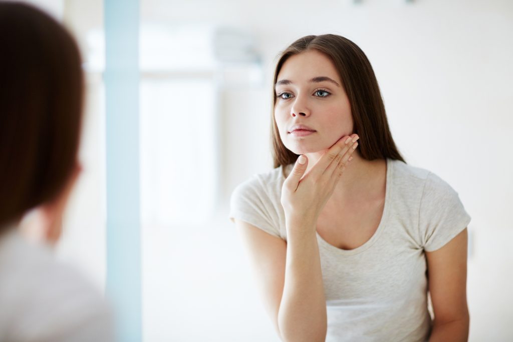 Young female looking at her face in mirror