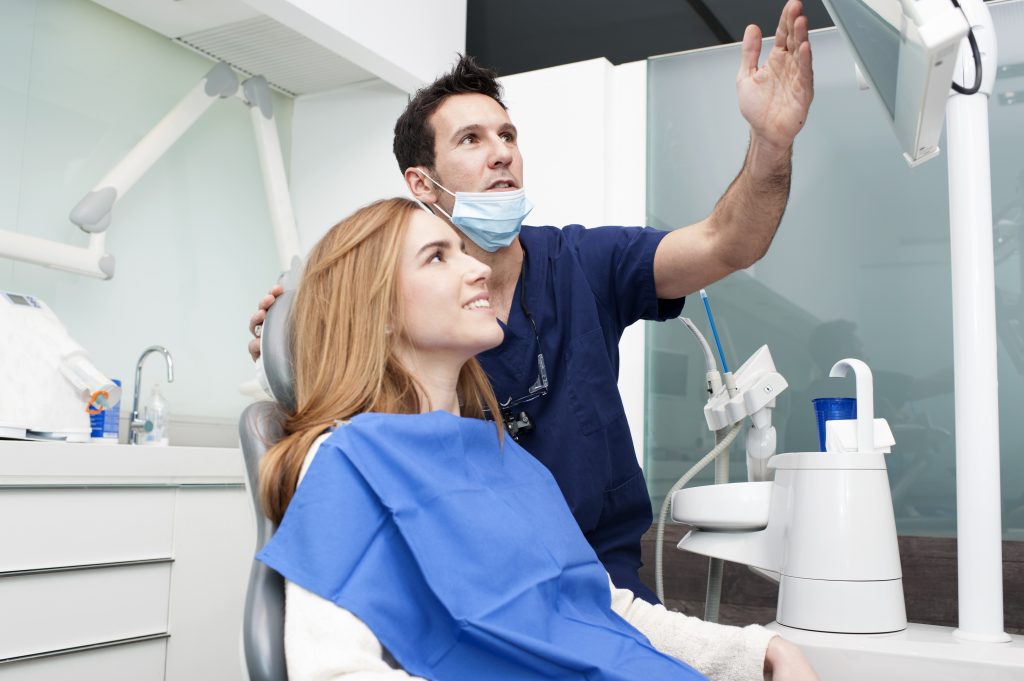 Dentist and patient looking at a screen atop of the room