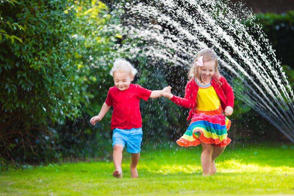 children playing with garden sprinkler