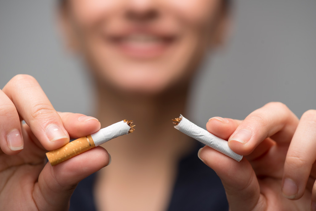 Young woman breaking down cigarette to pieces showing her will to quite smoking