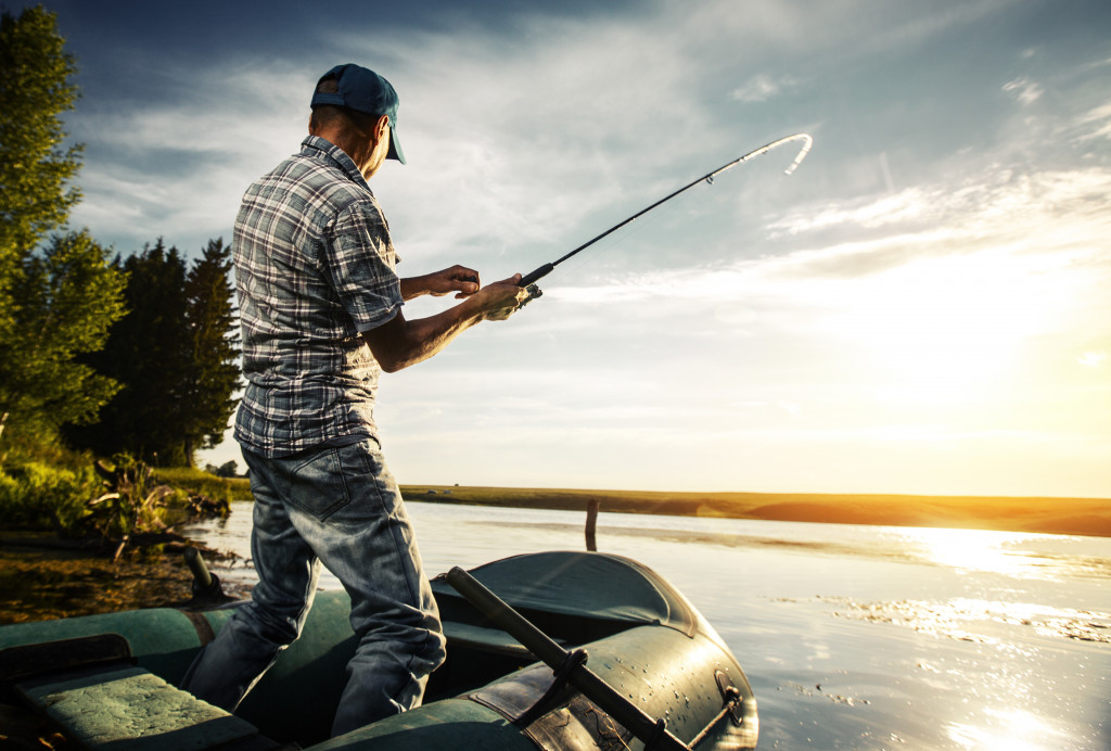 A man fishing from a boat on the pond at sunset