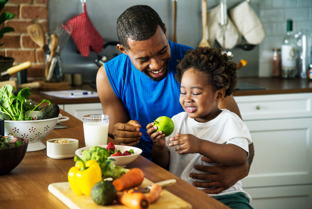 A father teaches his youngster about the value of a healthy eating while eating their breakfast, which they have prepared together.