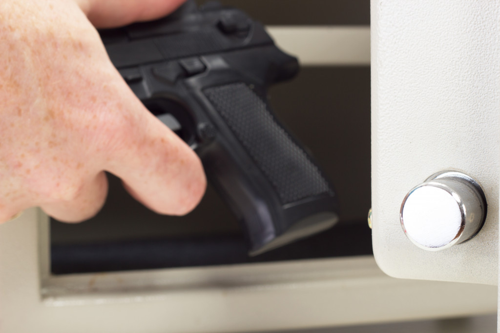 A person putting a gun in a gun safe