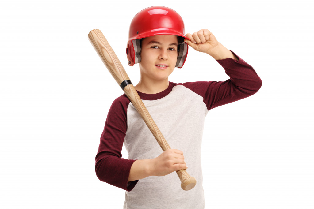 Kid with baseball bat in hand and safety gear helmet