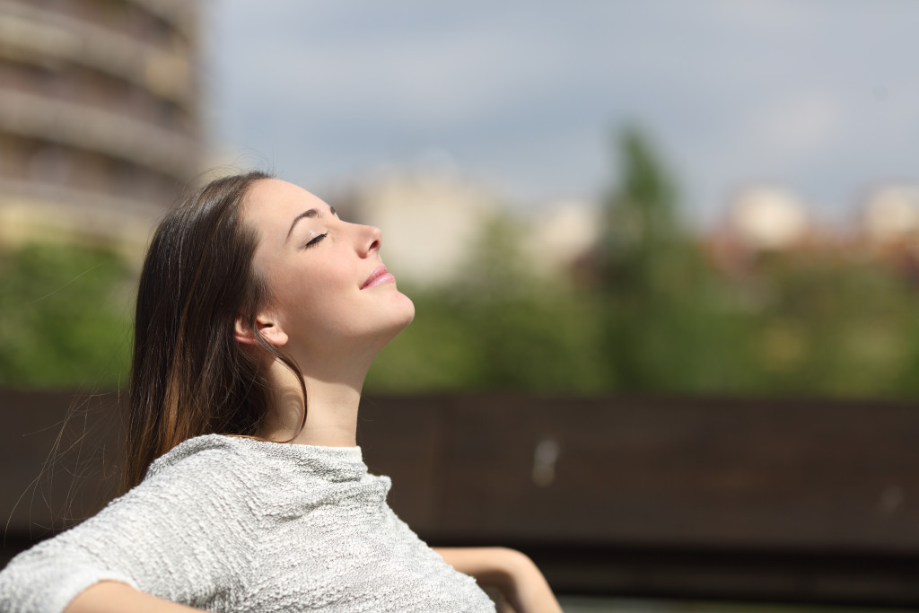 urban woman smiling under the sun while sitting on bench
