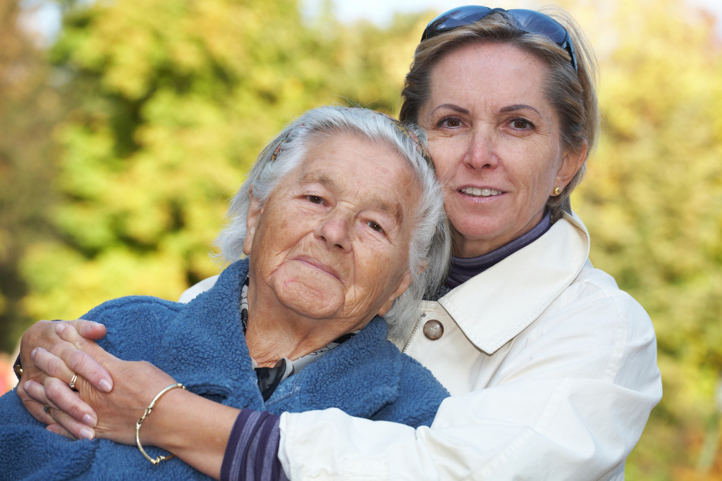 middle aged woman cuddles her elderly mother