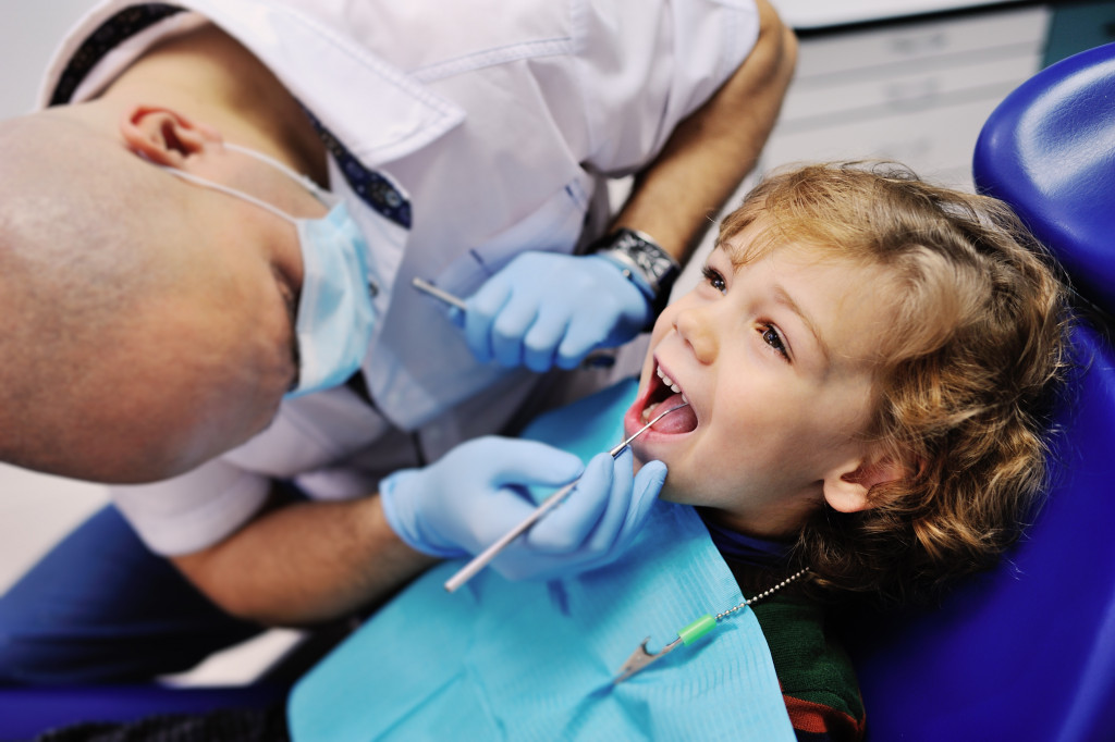 dentist checking on male child's teeth in dental clinic