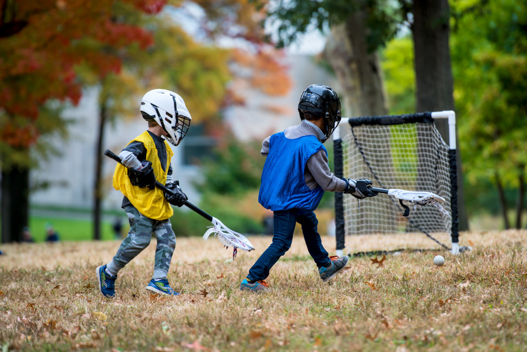 Children playing field hockey at a park.