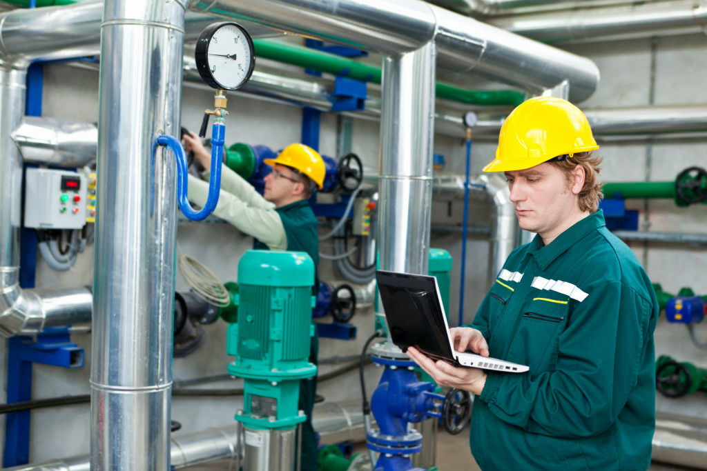 two male factory workers using laptop to monitor quality control in equipment