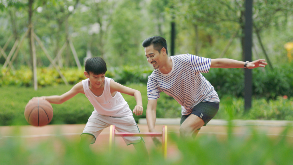 dad playing basketball with his son in park