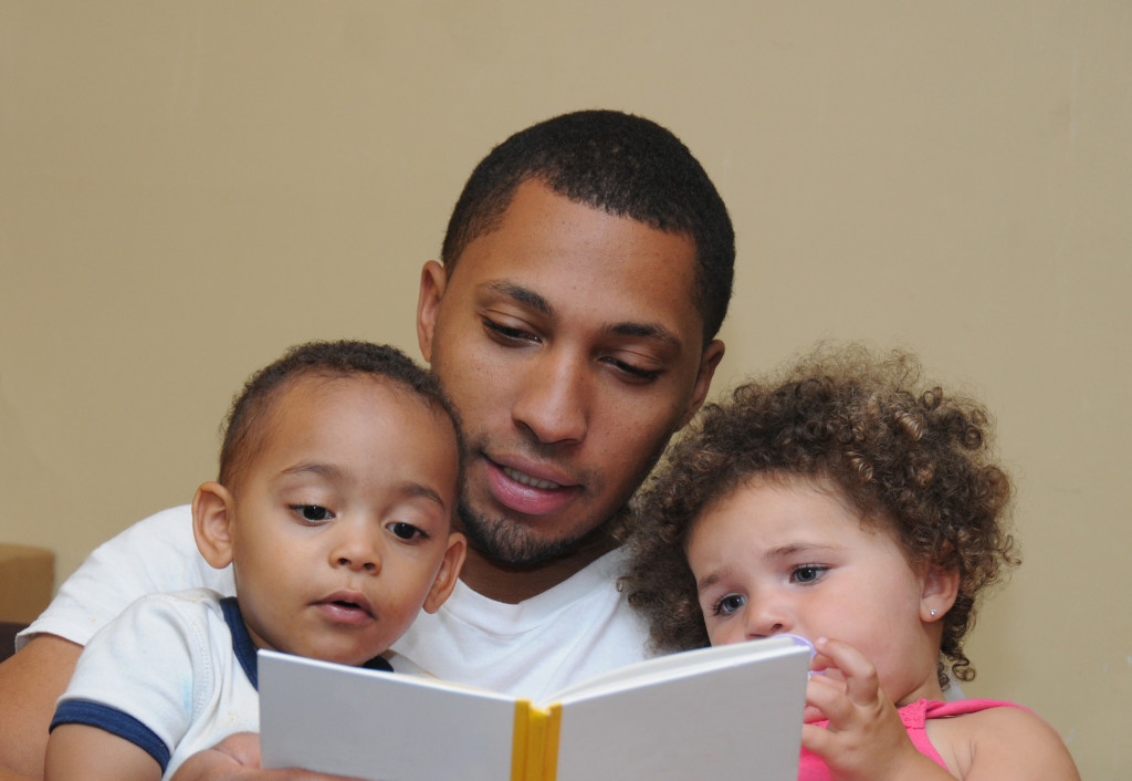 Father reading a storybook to his young children.