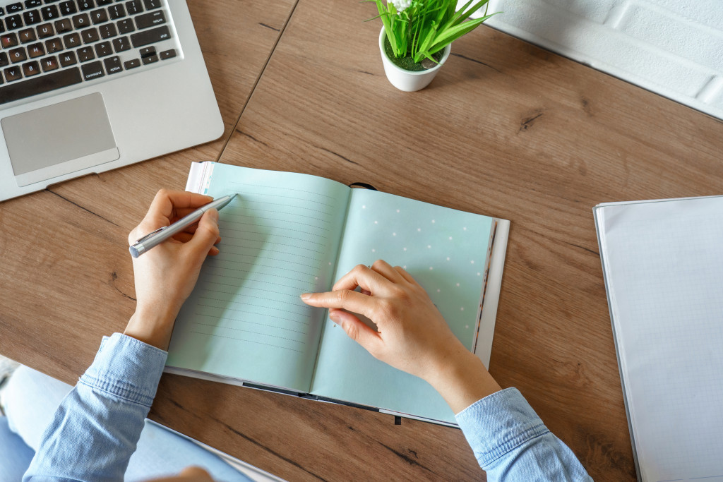 person writing in a journal with colored pages