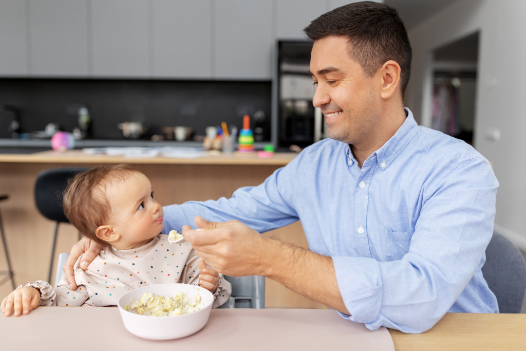 A parent helping baby eat otmeal