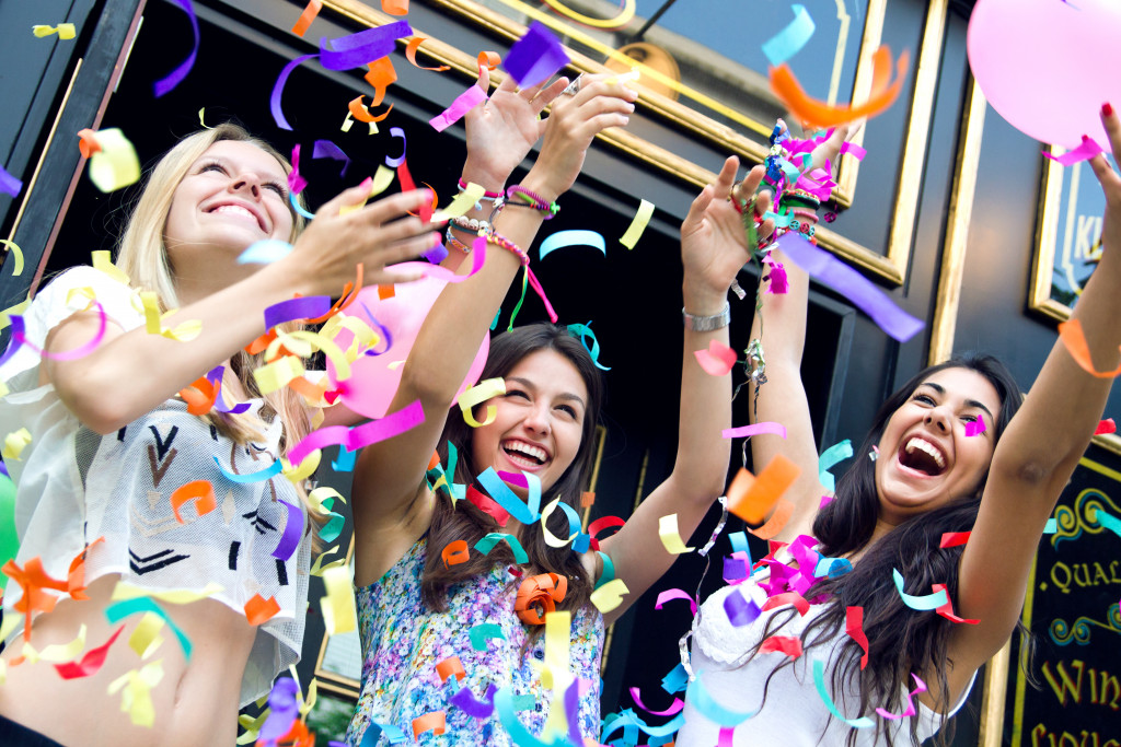 three teen girls smiling while partying with balloons and confetti