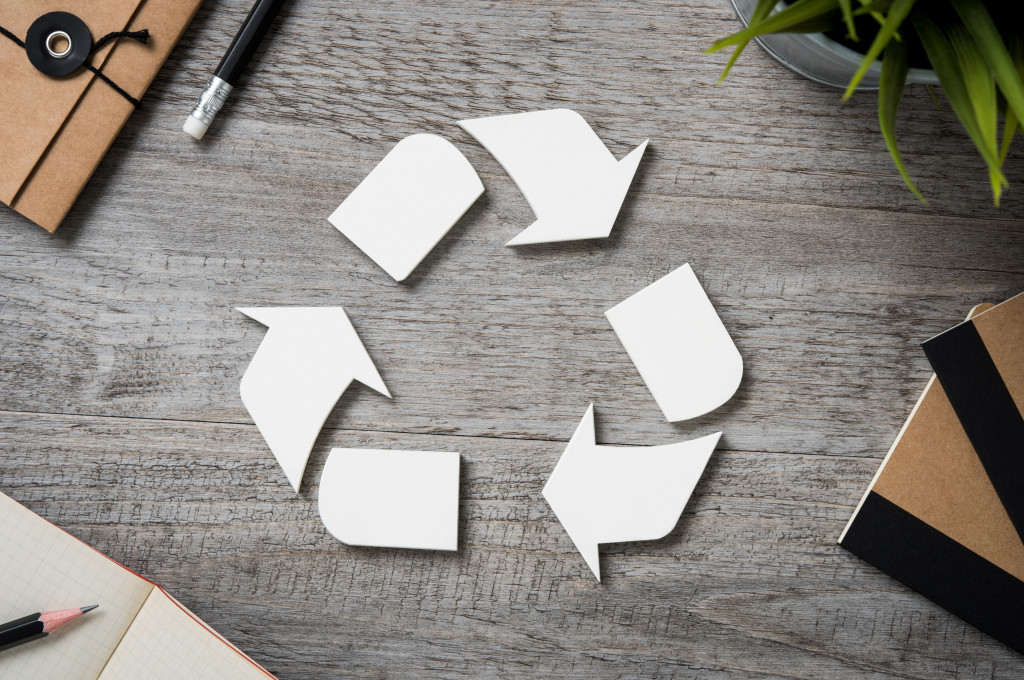 white recycling logo in wooden table with stuff around it