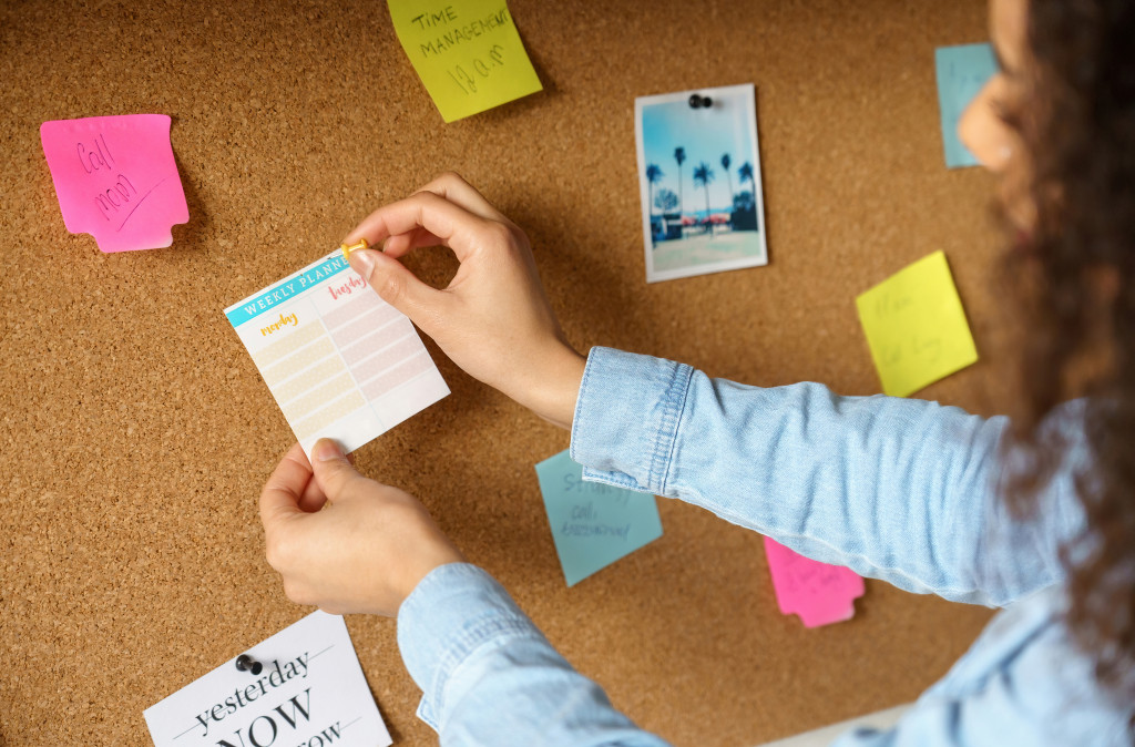 curly-haired teen sticking notes to bulletin board to represent tasks