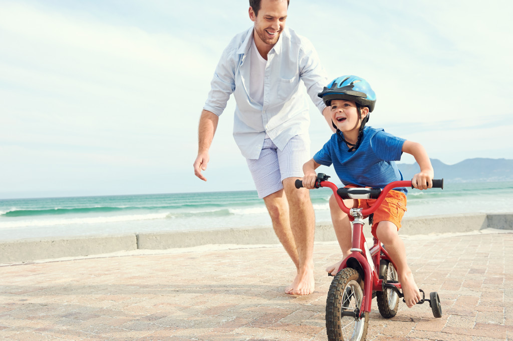 A father guiding his son while biking at the beach