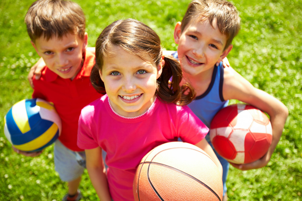  little children with balls smiling