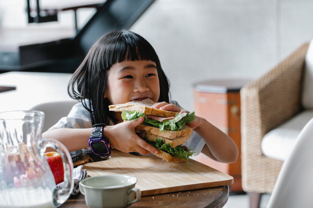 little girl eating vegetable sandwich