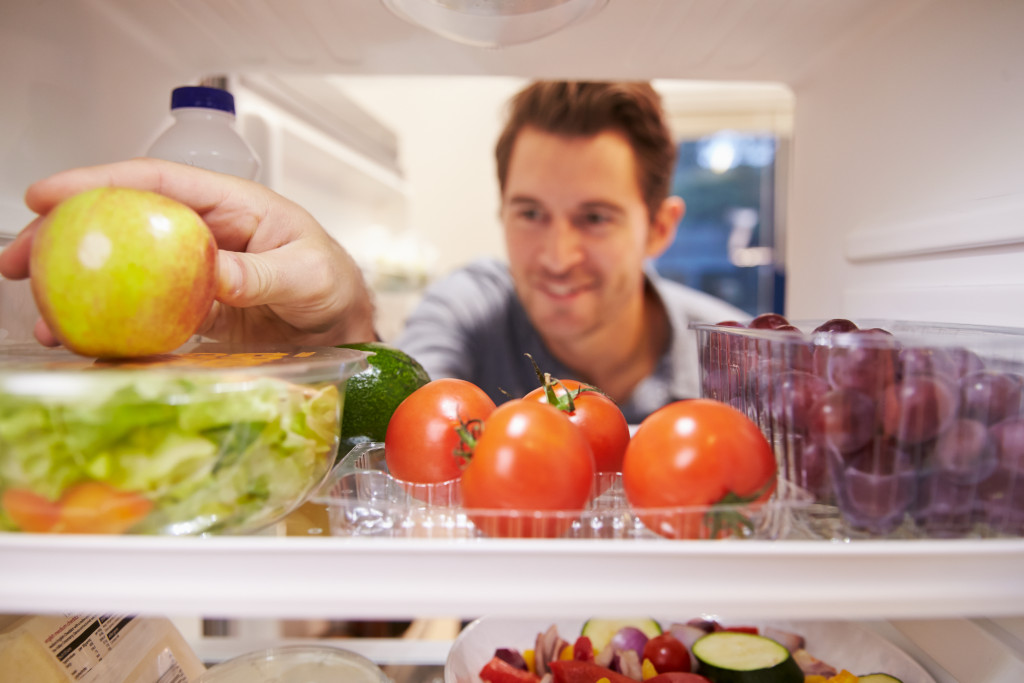 man checking food supplies in the fridge