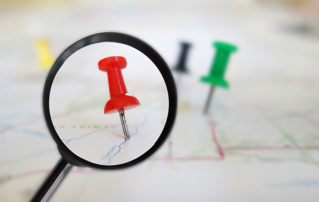 red pin in a map under a small magnifying glass