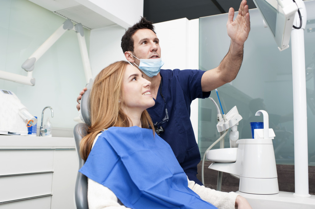 male dentist showing the procedure to a female patient