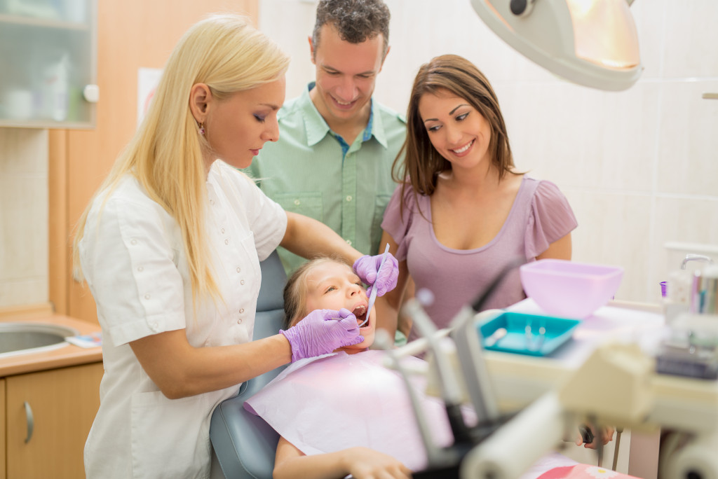 mom and dad watching their daughter dentist appointment