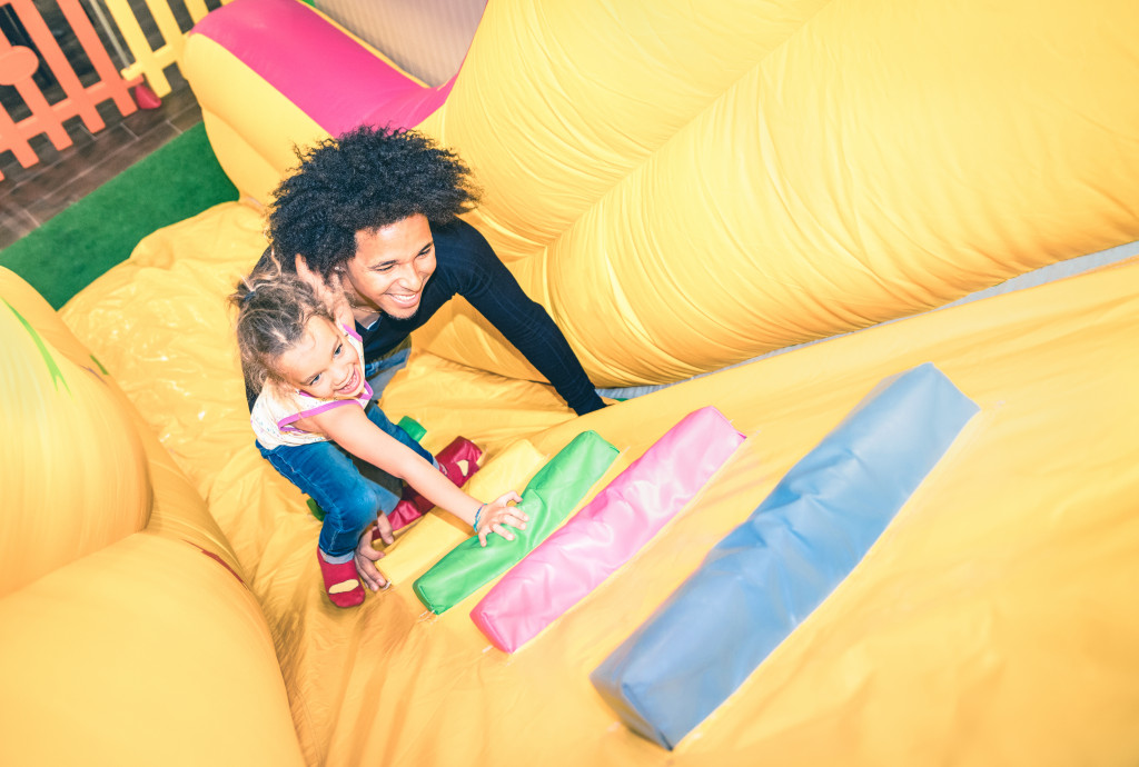 Father and daughter climbing an inflatable slide