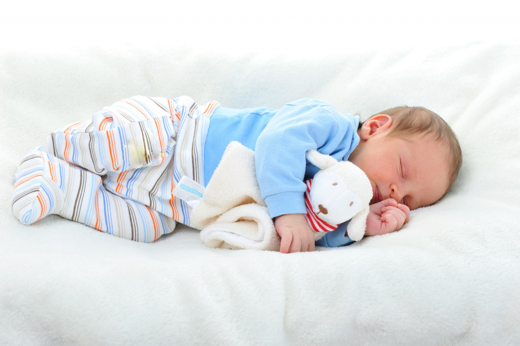 Baby sleeping in a bed while holding a toy.