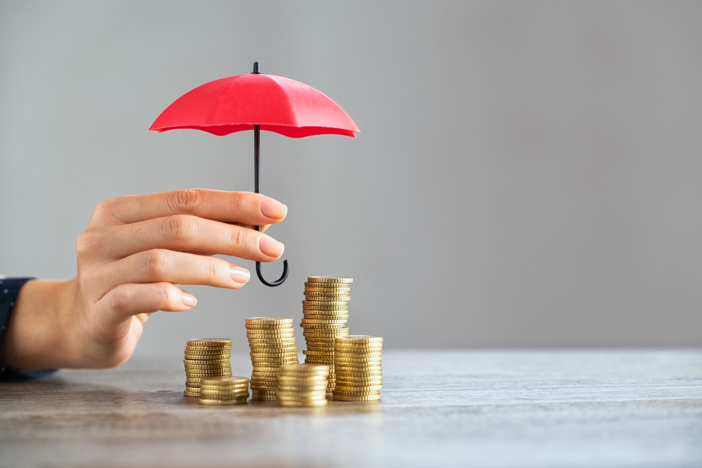 woman holding red umbrella over coins