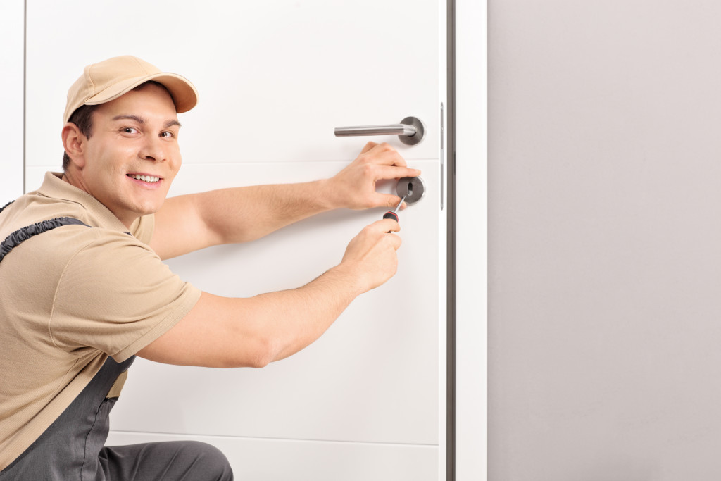 man installing door lock smiling