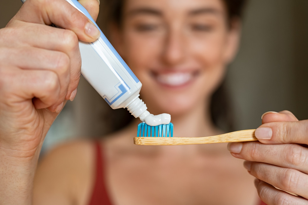 A woman putting toothpaste on a toothbrush