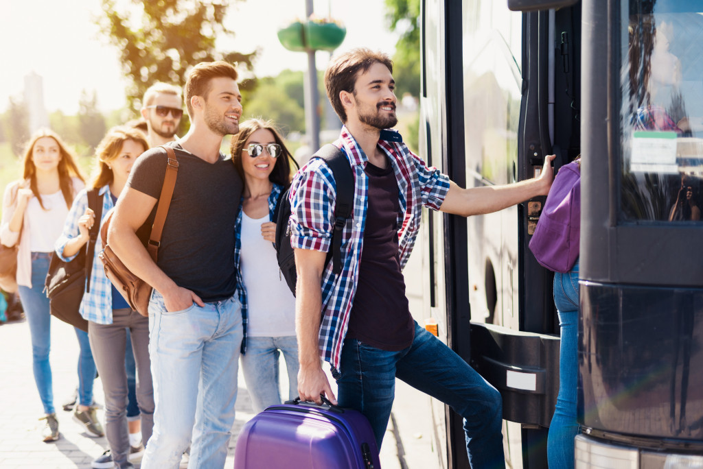 Young adults boarding a bus while traveling.