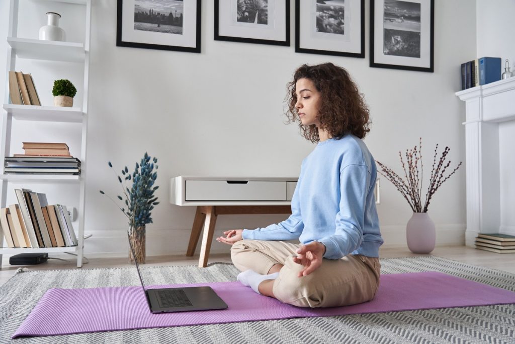 teenager meditating at home while watching yoga tutorial