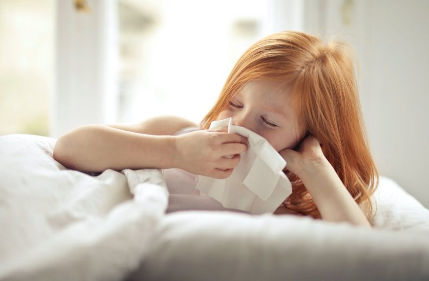 Girl with allergic rhinitis blowing her nose