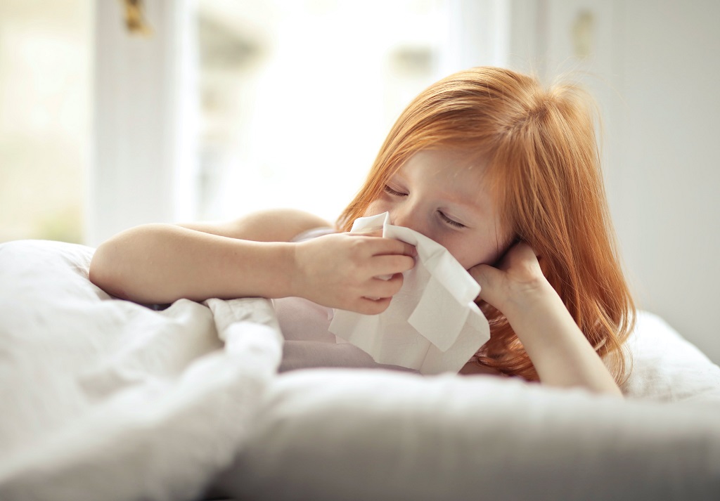 Girl with allergic rhinitis blowing her nose